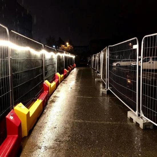 Illuminated security fencing and pathway at a construction site during nighttime hours